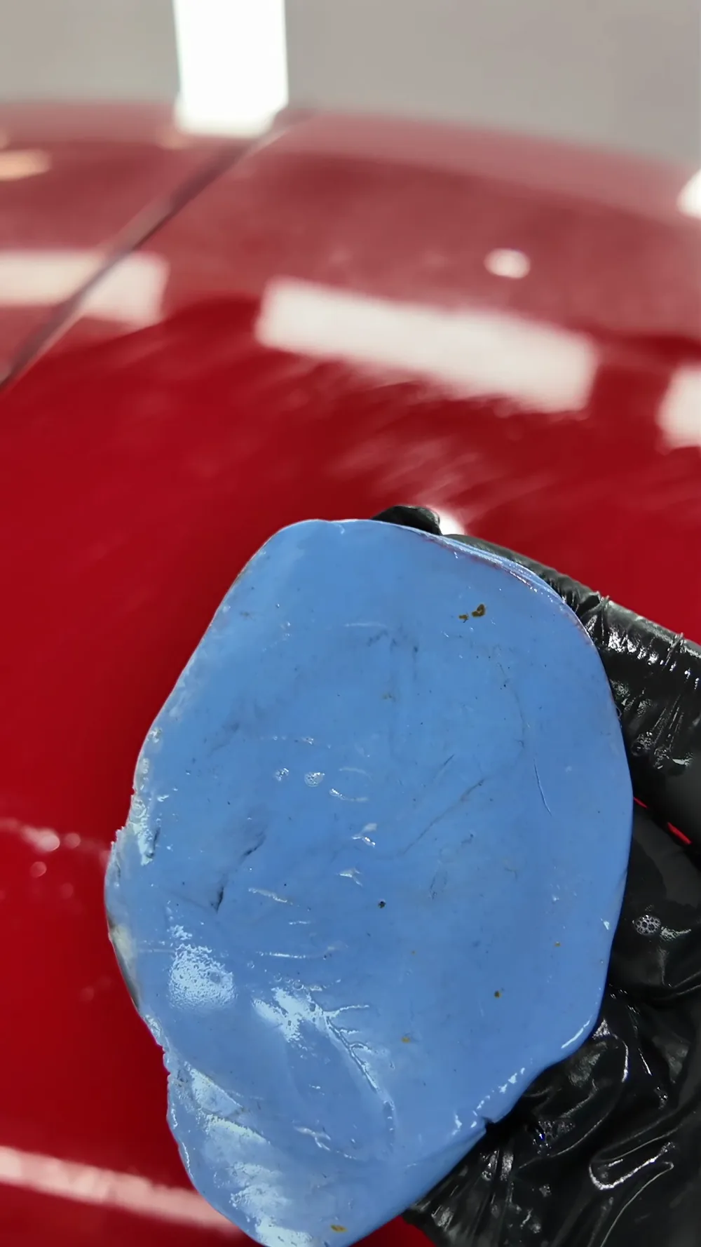 Blaue Lackknete mit eingelagerten Ablagerungen auf dem roten Lack des Porsche 964